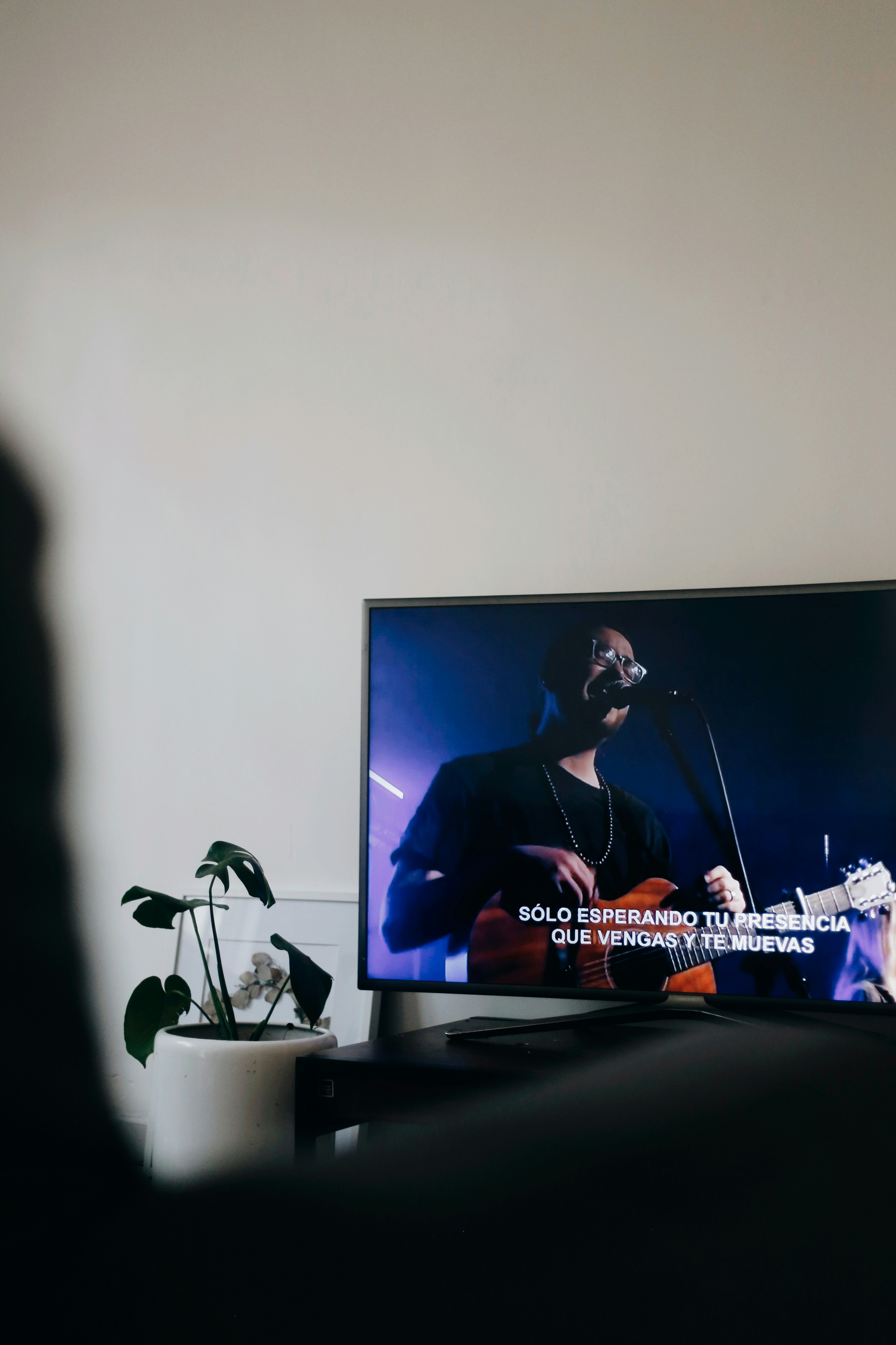 black flat screen tv turned on displaying man playing guitar